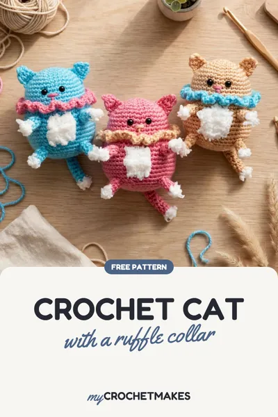 Three crocheted amigurumi cats in blue, pink and beige with ruffled collars and fluffy white bellies, sitting close together