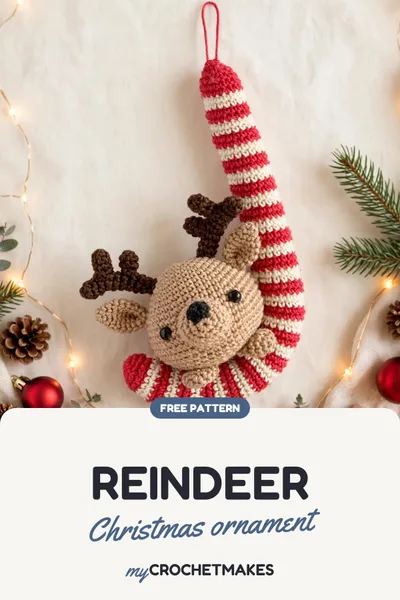 A crocheted reindeer ornament tucked into a red and white striped candy cane, hanging on a Christmas tree