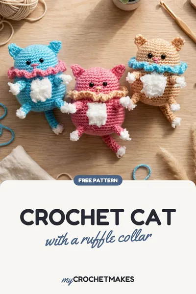 Three crocheted amigurumi cats in blue, pink and beige with ruffled collars and fluffy white bellies, sitting close together