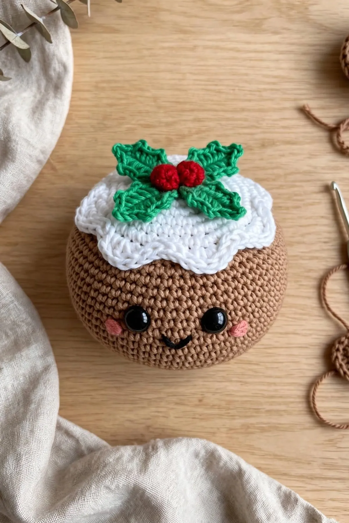 The crocheted Christmas pudding seen from above, showing the holly leaves and red berries on the white icing