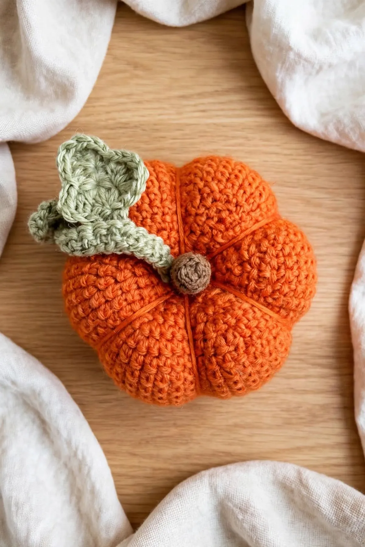 A crocheted pumpkin seen from above, showing six even sections around the brown stem